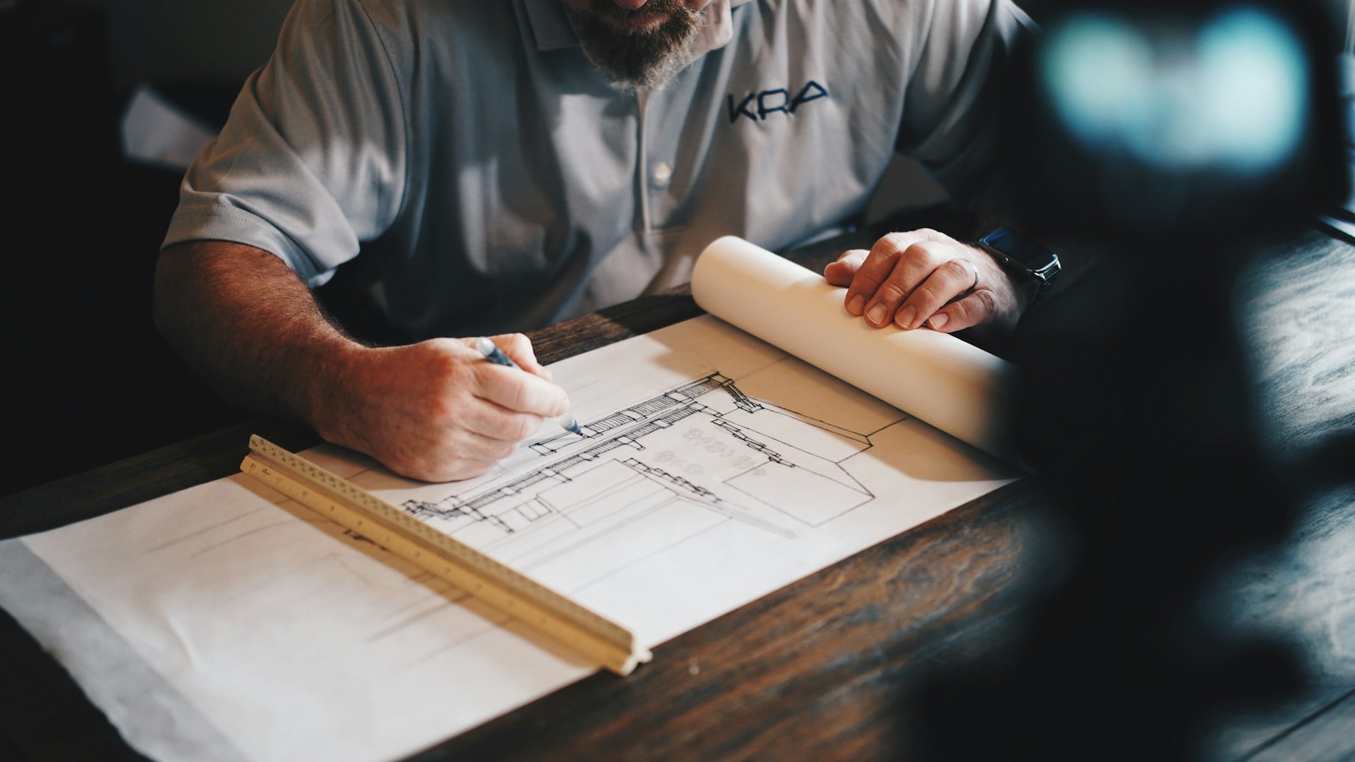Architect studying scale models and blueprints in a contemporary design studio for AACA architectural assessment